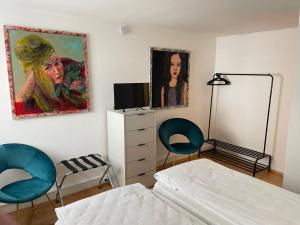 格平根Appartamenti Quattro Ducati的卧室配有两把椅子,墙上挂有绘画作品