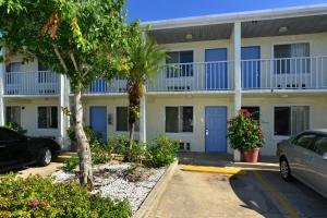 布雷登顿Americas Best Value Inn Bradenton-Sarasota的停车场内有蓝色门和树木的建筑