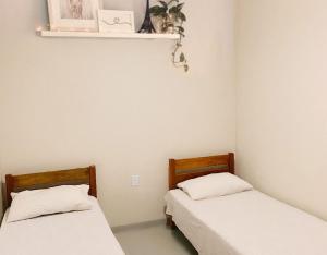 卡拉韦拉斯Pousada do beco的小客房内的两张床,配有白色床单