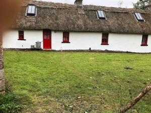 RooskeySweet Meadow A delightful romantic thatched cottage by river Shannon on 4 acres is for peace party family or work from home的白色的房子,有茅草屋顶,有院子