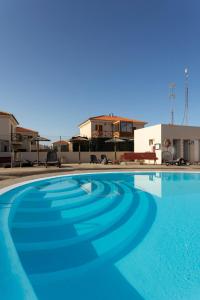 科拉雷侯Villa Calderón Hondo. Top design , views and pool Lajares-Corralejo的大楼前的大型蓝色游泳池