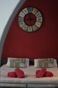圣胡斯托德斯韦尔恩Estudi Suite Desvern的床上的墙上挂着一个时钟,上面有红色枕头