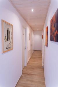 里乔内Affittacamere Ceccarini的走廊设有白色的墙壁、木地板和绘画作品