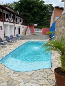 朱奎Pousada Canto Juquehy的一座大型蓝色游泳池,在院子里种有棕榈树