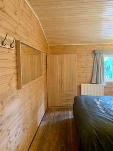 拉纳肯Het Zenhuisje的一间带木墙的卧室和一张位于客房内的床