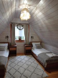 NarewkaSiedlisko Gruszki Puszcza Białowieska的阁楼卧室配有两张床和吊灯。