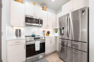 EphraimThe True Badger Honey House的厨房配有白色橱柜和不锈钢冰箱