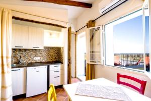波萨达Panoramic Loft con uso cucina ,Casa Raimonda, Ammentos Posada的厨房配有白色橱柜、桌子和窗户。