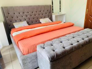 吉塞尼Arundinaria guest house的一张带橙色毯子和沙发的大床