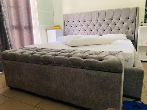 吉塞尼Arundinaria guest house的一张带灰色调的床头板和白色床单的床