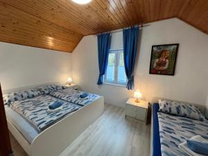索卡Apartmaji in Sobe Cuder的一间卧室设有两张床,窗户配有蓝色窗帘