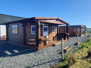邓韦根Harlosh Log Cabins的沙砾堆场上带门廊的小木屋