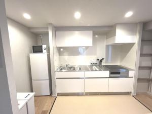东京KLASSO Tokyo Sumiyoshi Apartments的白色的厨房配有水槽和冰箱