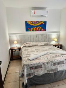 邦比尼亚斯Pousada Pedra da Gaivota的一间卧室配有一张带2个床头柜和2盏灯的床。