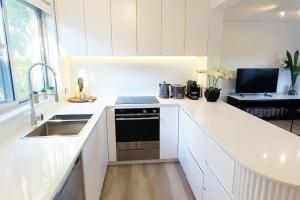 悉尼Moments to famous Bondi Beach的白色的厨房设有水槽和炉灶。