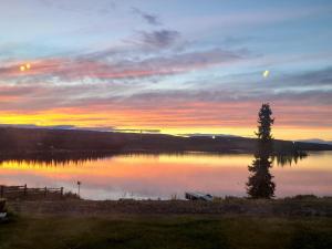 格伦纳伦Tolsona Lake Lodge的湖上日落,前方有树