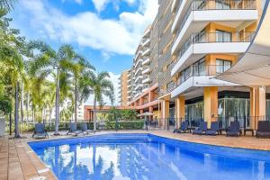 达尔文ZEN88 Esplanade: 3-BR Luxury Suite Near Waterfront的棕榈树建筑前的游泳池
