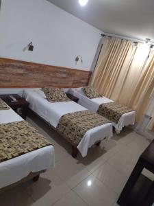 科皮亚波Amaru Hotel的酒店客房设有三张床和窗户。