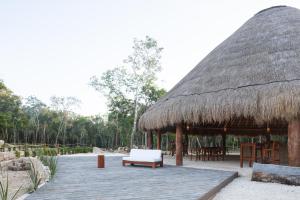 莫雷洛斯港Alma Maya Resort的一个带稻草屋顶的凉亭,配有长凳和桌子
