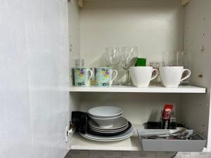 伦敦Premium Studio Flat 04 in Central London的厨房里装有杯子和碗碟的架子