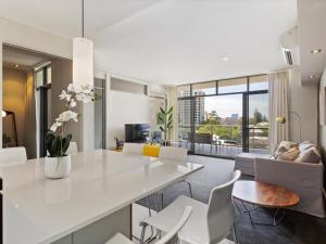 珀斯2bdrm Skyline Views - Prime for River, WACA, OPTUS Stadium的厨房以及带白色桌椅的起居室。