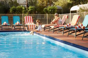 艾尔斯岩Outback Hotel的女人和孩子在游泳池玩耍