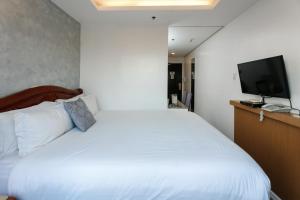 马尼拉丽晶套房大酒店的卧室配有白色的床和平面电视。