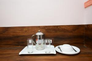 布巴内什瓦尔HOTEL SUSHREE INTERNATIONAL的茶壶和桌子上的玻璃杯