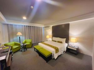马尼拉88万怡酒店 的酒店客房,配有一张床和两张绿色椅子