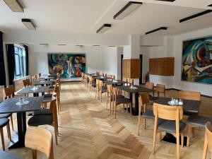 苏尔Olympia Hotel Suhl的一间带桌椅和绘画的用餐室