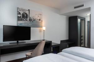 柏林柏林东城市酒店的一间卧室配有一张桌子、一台电视和一张床