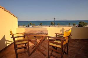 毕达哥利翁Βιλλα Βεατρικη/ villa Beatrice的海滩阳台的木桌和椅子
