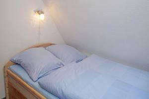 库克斯港Muschelsucher的一张带两个枕头的床和墙上的灯