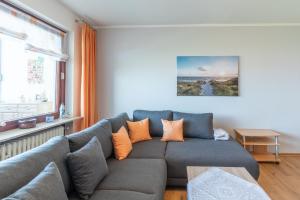 库克斯港Am Sahlenburger Strand Wohnung 8的客厅配有带橙色枕头的灰色沙发