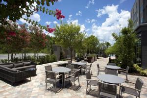 奥兰多Courtyard by Marriott Orlando South/Grande Lakes Area的庭院配有桌椅和树木