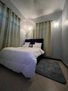 达累斯萨拉姆Romantic, Stunning & Authentic Ensuited Master Bedroom的卧室配有一张白色大床和吊灯。