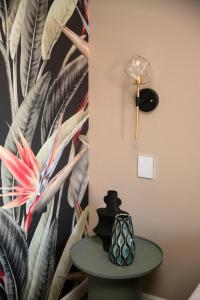 蒂米什瓦拉Cosmopolita Boutique Hotel的一张桌子,墙上挂着一盏灯,墙上挂着热带壁纸