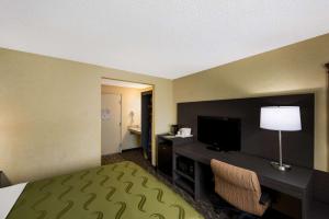 西塔科Quality Inn SeaTac Airport-Seattle的酒店客房配有一张床和一张书桌及一台电视
