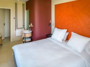 PamandziIbis Styles Mayotte Aéroport的一间卧室配有一张白色大床和橙色床头板