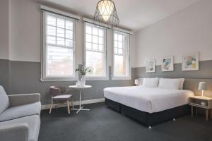 悉尼阿尔提莫酒店的一间卧室配有一张床、一把椅子和一张沙发