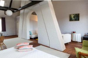 SoigniesLes Greniers de Madelgaire的一间设有白色砖墙和一张带枕头的床的客房