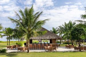 格卢市社Melia Vinpearl Cua Hoi Beach Resort的一个带椅子和棕榈树的凉亭