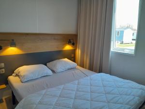 RijkevorselVakantiepark Breebos的卧室配有一张带两个枕头的床和窗户