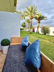 阿罗纳Stunning lovely flat with Pool and strong Wi-Fi的两块蓝色枕头坐在长椅上,长满棕榈树