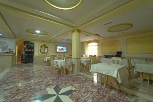 地拉那Olimpic Hotel的一间在房间内配有桌椅的餐厅