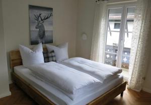 加尔米施-帕滕基兴Alpenhof Garnihotel & Ferienwohnungen的一间卧室配有一张带白色床单的床和一扇窗户。