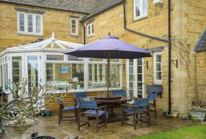 奇平卡姆登Chipping Campden - Cotswolds private house with garden的庭院配有桌椅和遮阳伞。