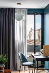 拉罗谢尔Maison des Ambassadeurs的客房设有桌子、椅子和窗户。