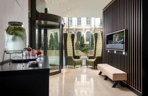 布加勒斯特Leonardo Hotel Bucharest City Center的客厅配有椅子、桌子和电视