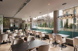 布加勒斯特Leonardo Hotel Bucharest City Center的餐厅设有桌椅和窗户。